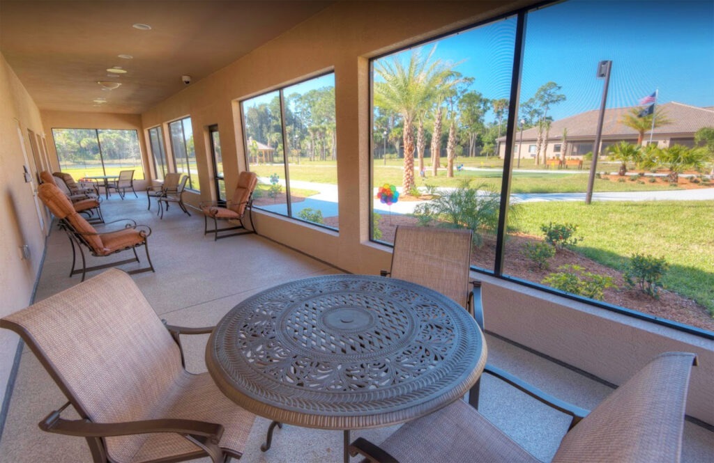 A screened-in porch provides a shaded space for residents to enjoy fresh air at Palm Bay Memory Care, a community offering senior living near Melbourne.